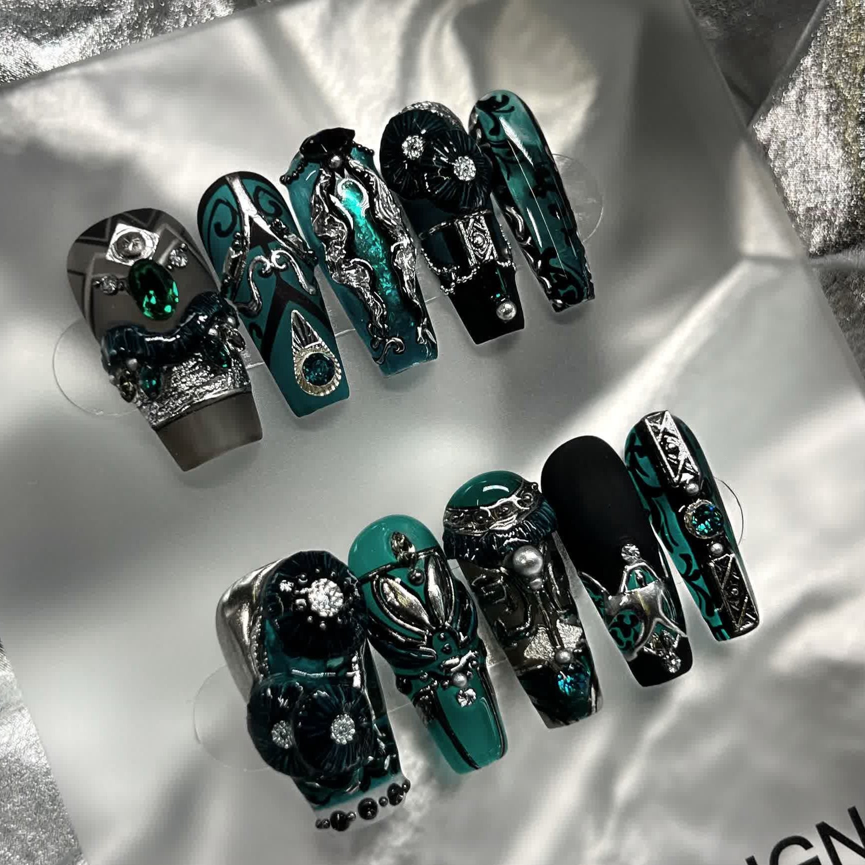 Intricately designed green and black nail art with a mix of textures